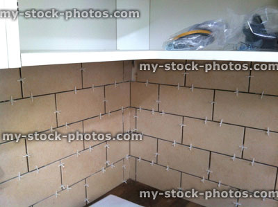 Stock image of kitchen being tiled, brick effect light brown stone / ceramic tiles