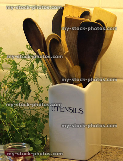 Stock image of wooden kitchen utensils in pot, fresh herbs, parsley