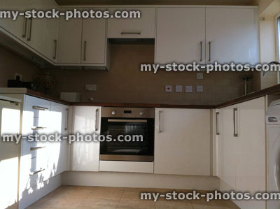 Stock image of modern kitchen with white glossy cabinets, cooker, sink, wooden worktops