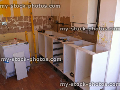 Stock image of new kitchen being fitted, kitchen fitters, cabinets / cupboards, old gas boiler