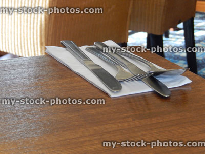 Stock image of cutlery on wooden table, spoon, knife and fork, white napkin