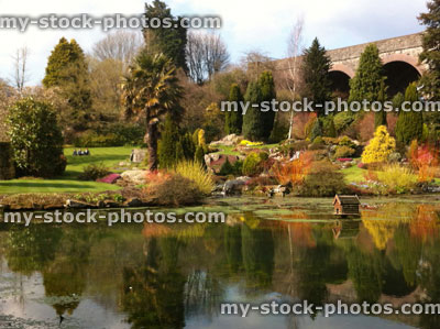 Stock image of duck pond with rockery garden, stone viaduct bridge