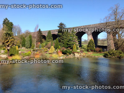 Stock image of duck pond with rock garden, trees, viaduct bridge