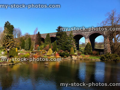 Stock image of mill pond with rockery garden, stone viaduct bridge
