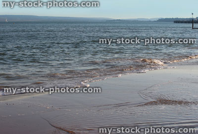 Stock image of glistening sea waves lapping sand on seaside beach