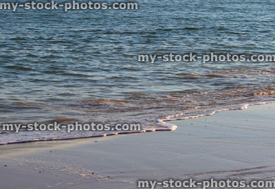 Stock image of gentle sea waves lapping the beach shore (close up)