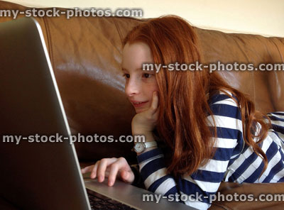 Stock image of girl using laptop on sofa, researching homework