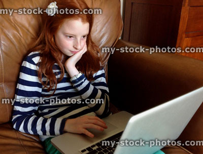 Stock image of girl using a laptop on leather sofa