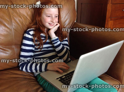 Stock image of girl using Apple laptop for homework, laughing at website