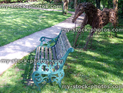 Stock image of an iron bench and willow wicker horse sculpture