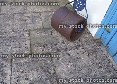 Stock image of rusty, metal, concrete lawn roller, on patio slabs