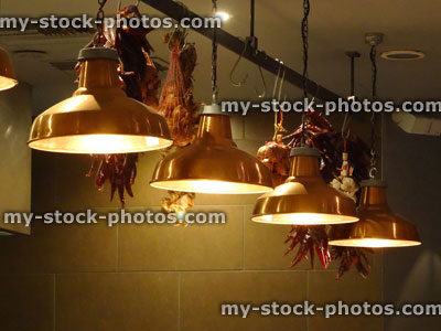 Stock image of stylish hanging copper kitchen lamps / lights in row