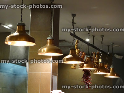 Stock image of copper hanging lamps / lights in row, restaurant kitchen