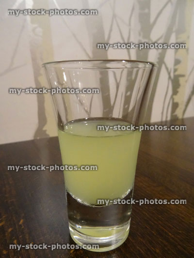Stock image of limoncello liqueur in small shot glass / lemon liqueur, alcohol / alcoholic drink