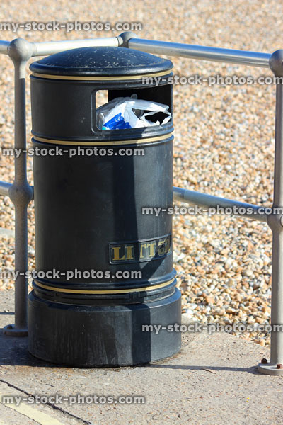 Stock image of black metal littler bin at beach with rubbish