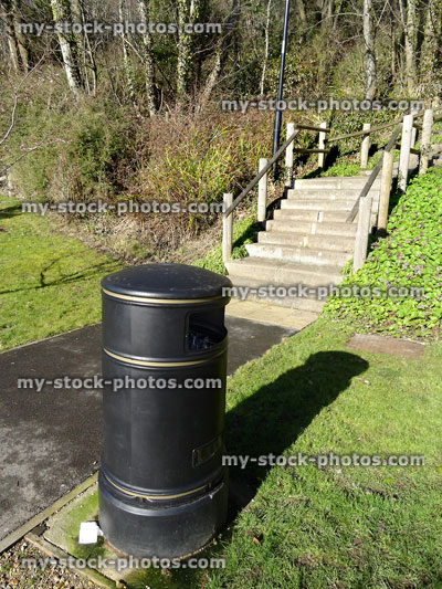 Stock image of round litter bin in park, collecting rubbish by pathway