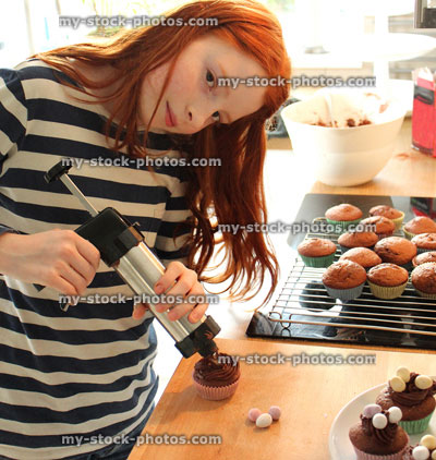 Stock image of girl in a kitchen icing cakes