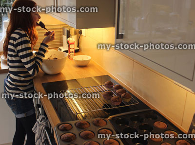 Stock image of girl in a kitchen eating frosting
