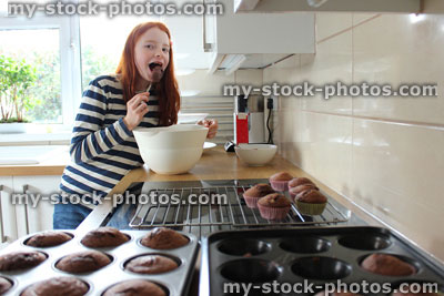 Stock image of girl in a kitchen eating cake mix