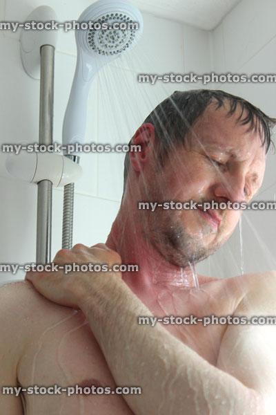 Stock image of young man with beard taking a shower, washing hair