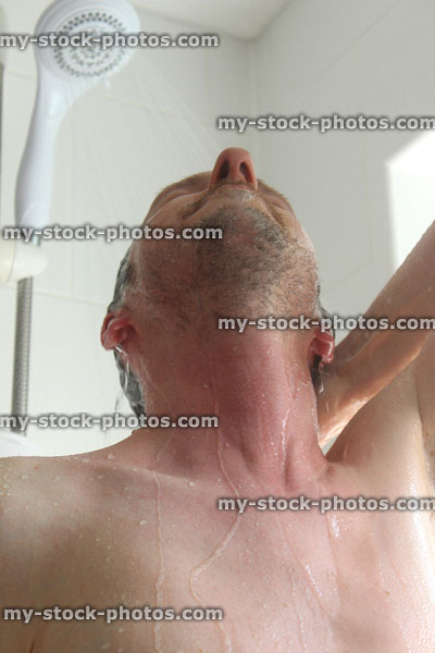 Stock image of young man taking a shower, looking upwards, washing / rinsing hair