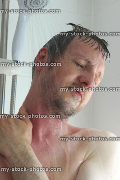 Stock image of young man with beard taking a shower, rinsing / washing hair
