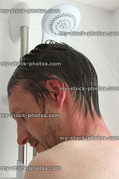 Stock image of young man taking a hot shower, washing hair, eyes closed