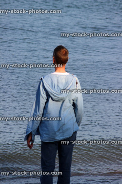 Stock image of young man paddling in sea, beach, seaside, denim hoodie