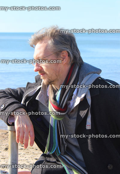 Stock image of middle aged man with grey hair, on beach in winter