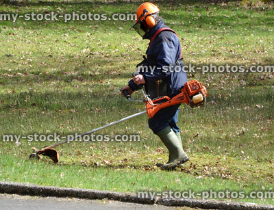Stock image of gardener wearing safety equipment and headphones, strimming lawn