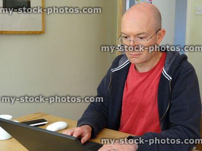 Stock image of man working at home using laptop on table