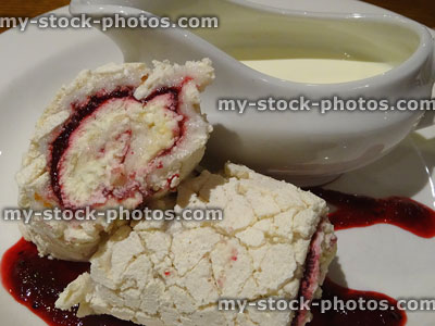Stock image of red berry roulade meringue cake with jug of cream