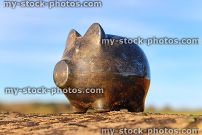 Stock image of silver metal piggy bank pig, tarnished / rusty, blue sky background