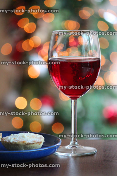 Stock image of glass of red wine with mince pie and fairylights