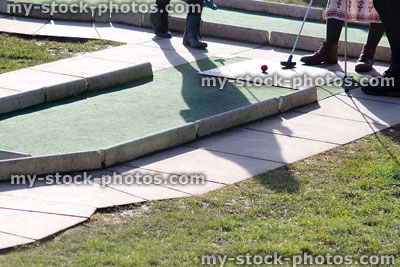 Stock image of people playing on mini golf course, golfing clubs / putters
