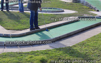 Stock image of children playing on mini golf course, hitting ball