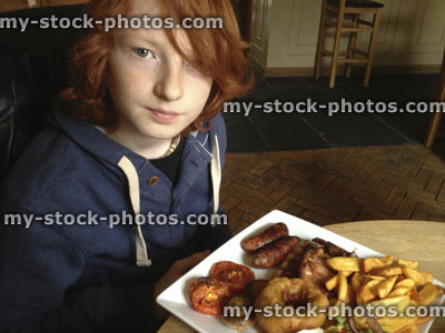 Stock image of teenage boy eating mixed grill with steak