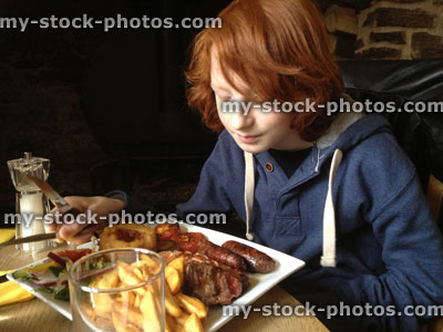 Stock image of teenage boy eating mixed grill with steak