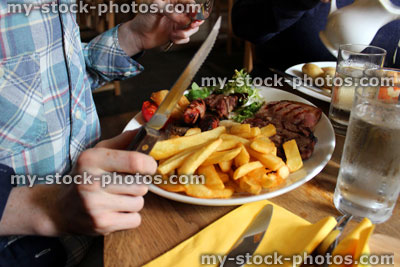 Stock image of boy eating mixed grill meal in restaurant, steak and chips