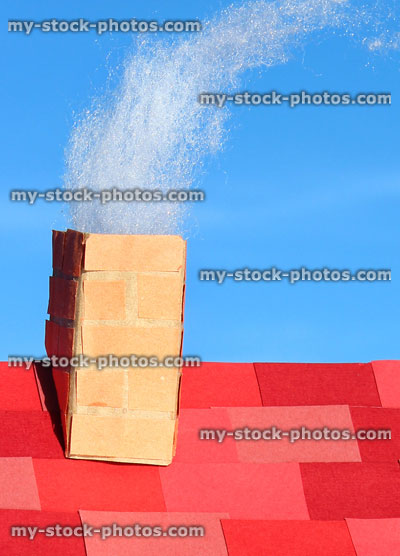 Stock image of model cardboard house roof with chimney stack / smoke