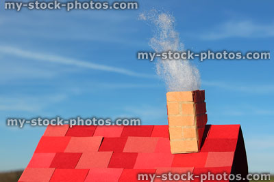 Stock image of smoking chimney on homemade model house / cardboard roof