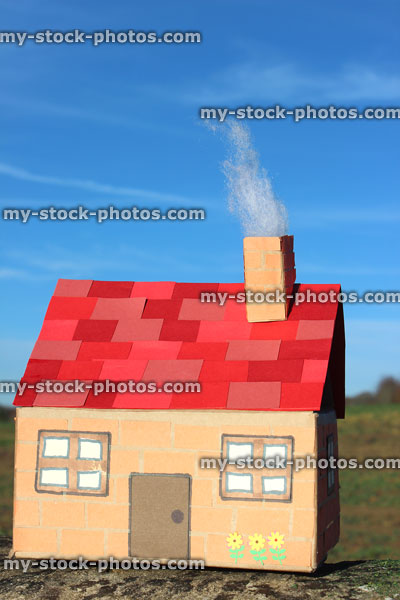 Stock image of model card house with red roof tiles, smoking chimney