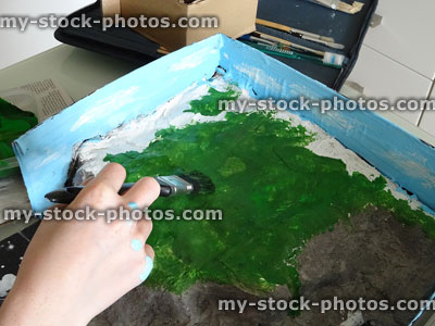 Stock image of child painting seaside model for school homework project