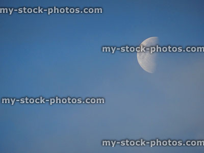 Stock image of half moon at end of day, against blue sky