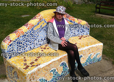 Stock image of girl sat on homemade mosaic bench in style of Gaudí