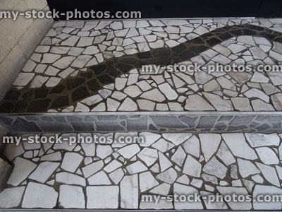 Stock image of mosaic tiled floor with black, white, grey broken tiles