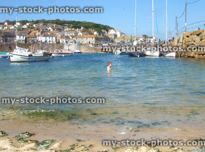 Stock image of young boy in sea at Mousehole harbour, Cornwall