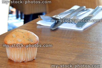 Stock image of freshly baked muffin on wooden table, cutlery, napkin