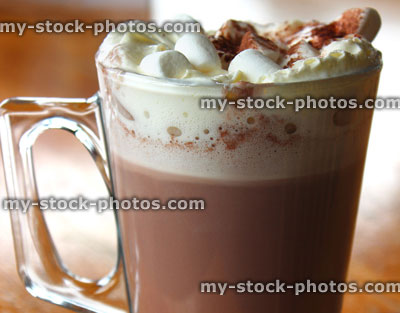 Stock image of glass mug of hot chocolate, cream, marshmallows, cocoa powder