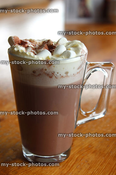 Stock image of glass mug of hot chocolate, cream, marshmallows, cocoa powder